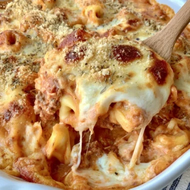 Cheesy baked tortellini casserole with meat sauce in a serving dish
