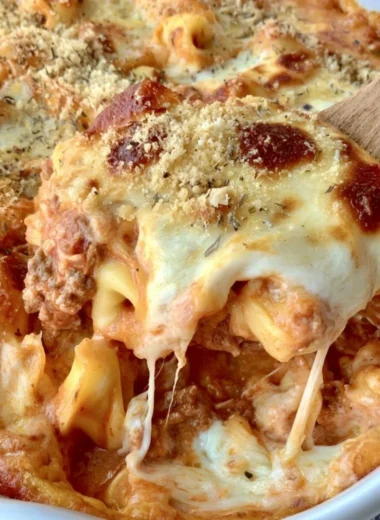 Cheesy baked tortellini casserole with meat sauce in a serving dish