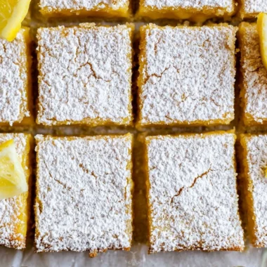 Delicious cozy lemon bars topped with powdered sugar on a white plate
