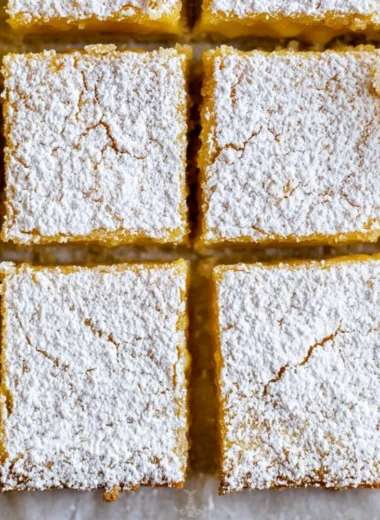 Delicious cozy lemon bars topped with powdered sugar on a white plate
